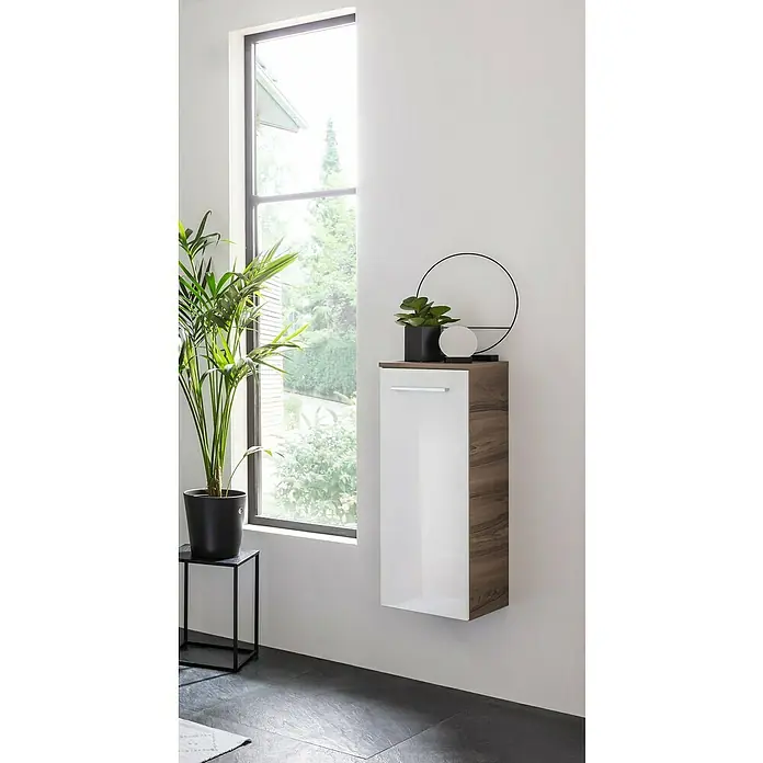 Fackelmann Verona Midischrank - B x T x H: 30,2 x 32 x 82,6 cm, DIN Anschlag: Rechts, Weiß Hochglanz/Nussbaum - Das Bild zeigt einen modernen weißen Wandschrank mit Holzdetails, dekoriert mit Pflanzen und einer Lampe.