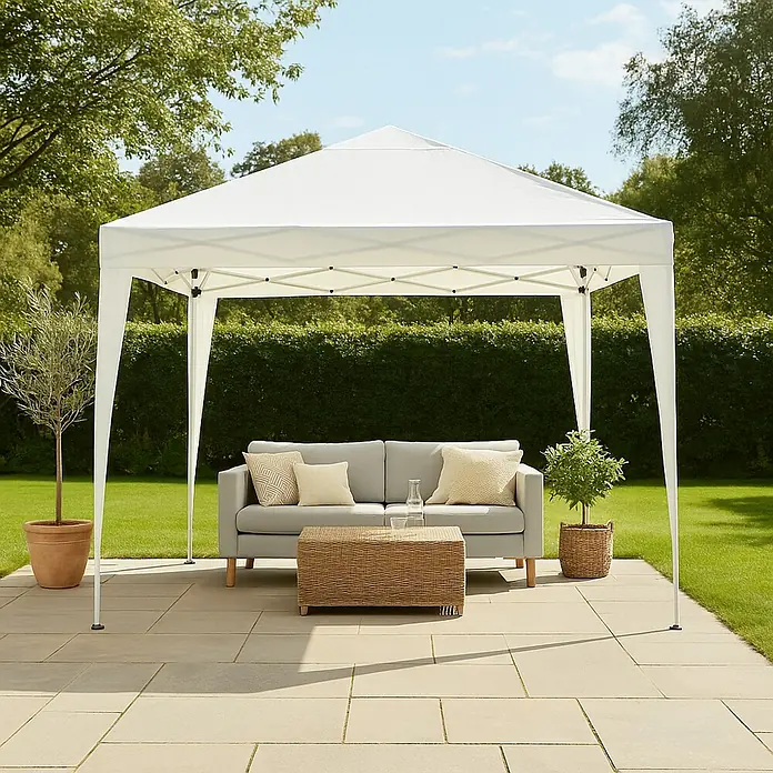 Sunfun Carpa plegable Easy Up - An x Pr: 300 x 300 cm, Blanco - Imagen de un cenador de jardín blanco con un sofá y una mesa en un patio, rodeado de vegetación.