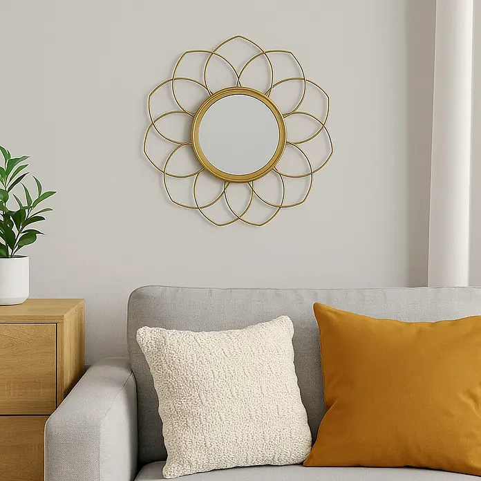 Espejo de pared Flor Oro - 27 x 27 cm - Una toma de primer plano que muestra un espejo de pared redondo con marco dorado y diseño de pétalos, que cuelga sobre un sofá gris con cojines.