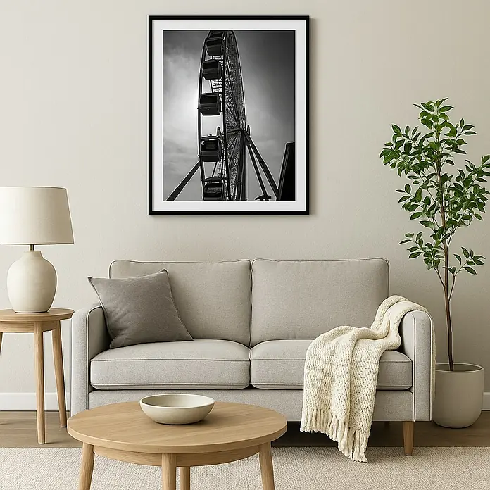 Cuadro Noria - An x Al: 40 x 50 cm, 1 pzs. - Fotografía en blanco y negro de una noria en un marco negro colgada sobre un sofá claro en una sala de estar.