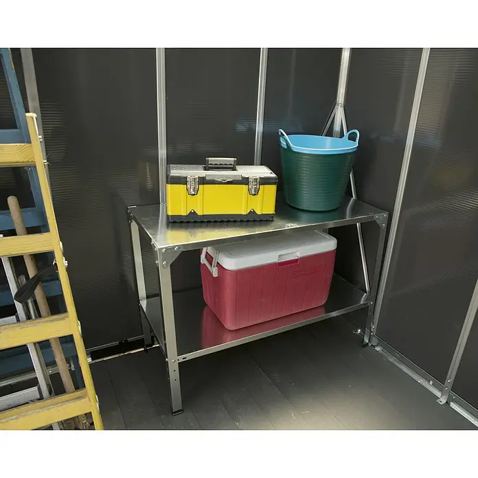 Palram – Canopia Gartenhaus - Außenmaß inkl. Dachüberstand (B x T): 332 x 271 cm, Kunststoff, Grau, Mit Boden - Werkstattszenario mit Werkzeugkasten, Eimer und Kühlbox auf einem robusten Metalltisch in einer Werkstatt oder Garage.