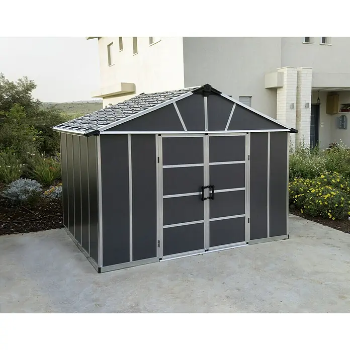Palram – Canopia Gartenhaus - Außenmaß inkl. Dachüberstand (B x T): 332 x 271 cm, Kunststoff, Grau, Ohne Boden - Ein graues Gartenhaus mit Doppeltüren und silberfarbenem Rahmen steht auf einer betonierten Fläche. Es bietet viel Stauraum für Gartengeräte.