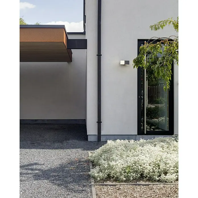 Lutec Cuba LED-Außenwandleuchte - 24 W, 10 x 9,5 x 21,3 cm, Anthrazit/Weiß, IP54 - Außenansicht eines modernen Hauses mit stilvoller Beleuchtung, sauberem Design und gepflegtem Garten.