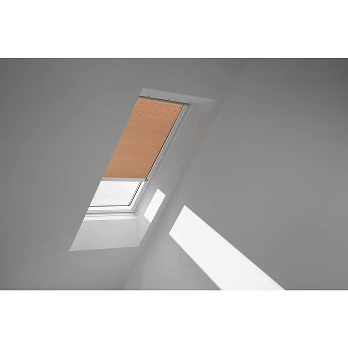 Velux Dachfensterplissee FSC S08 1049KWL - Farbe: Apricot - 1049KWL, Farbe Schiene: Weiß, Solarbetrieben - Das Bild zeigt ein Dachfenster mit einem orangefarbenen Plissee, das teilweise geschlossen ist. Es befindet sich in einem hellen Raum mit schrägen Wänden.
