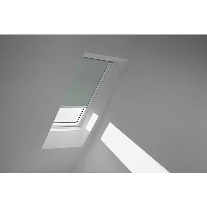 Velux Dachfensterplissee FSC UK04 1168KWL - Farbe: Blassgrün - 1168KWL, Farbe Schiene: Weiß, Solarbetrieben - Ein Dachfenster mit teilweise heruntergelassenen Jalousien in einem hellen Raum, das Licht und Schatten erzeugt.