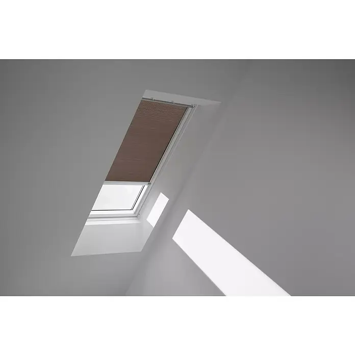 Velux Dachfensterplissee FMC MK06 1165K - Farbe: Muskat - 1165K, Farbe Schiene: Aluminium, Elektrisch - Das Bild zeigt ein Dachfenster mit einem braunen Rollo in einem hellen Raum. Das Rollo ist teilweise heruntergelassen.