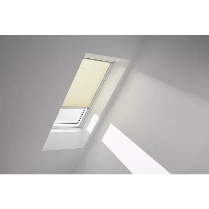 Velux Dachfensterplissee FSL F06 1278K - Farbe: Cremebeige - 1278K, Farbe Schiene: Aluminium, Solarbetrieben - Dachfenster mit einem hellen Faltrollo, das teilweise geöffnet ist und Licht hereinlässt. Helle Wände reflektieren das Tageslicht.