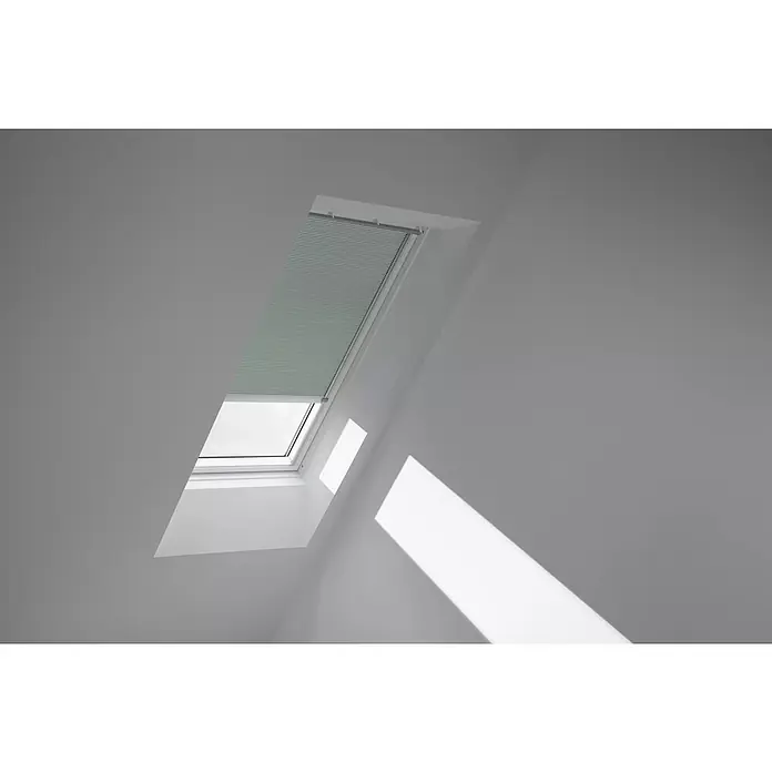 Velux Dachfensterplissee FSC M06 1168K - Farbe: Blassgrün - 1168K, Farbe Schiene: Aluminium, Solarbetrieben - Helle Innenaufnahme eines Dachfensters mit Rollo, das teilweise geschlossen ist und Sonnenlicht hereinlässt, das sich an der Wand spiegelt.