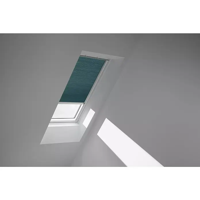 Velux Dachfensterplissee FSC M06 1173K - Farbe: Petrol - 1173K, Farbe Schiene: Aluminium, Solarbetrieben - Dachfenster mit blauem Rollo im geöffneten Zustand, das Licht und Schatten auf die Wand wirft. Praktischer Sonnenschutz für Dachgeschosswohnungen.