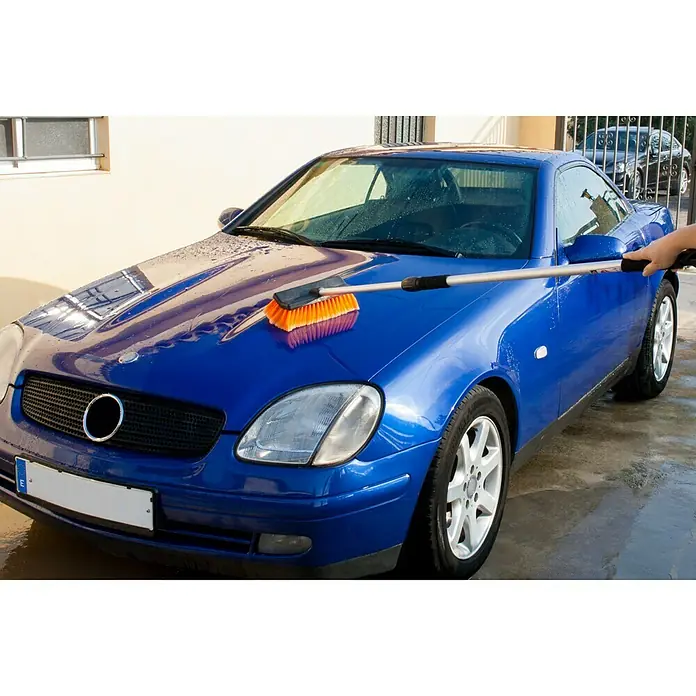Cepillo para automóviles - Telescópico - Un coche azul está siendo limpiado con un cepillo de lavado de autos para mantenerlo limpio y brillante.