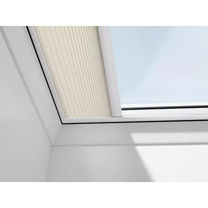 Velux Dachfensterplissee FMG 150150 1259KWL - Farbe: Hellbeige - 1259KWL, Farbe Schiene: Weiß, Elektrisch - Nahaufnahme einer Dachfensterjalousie, die teilweise geschlossen ist und sanftes Licht filtert. Die helle Farbe der Jalousie harmoniert mit der weißen Decke.