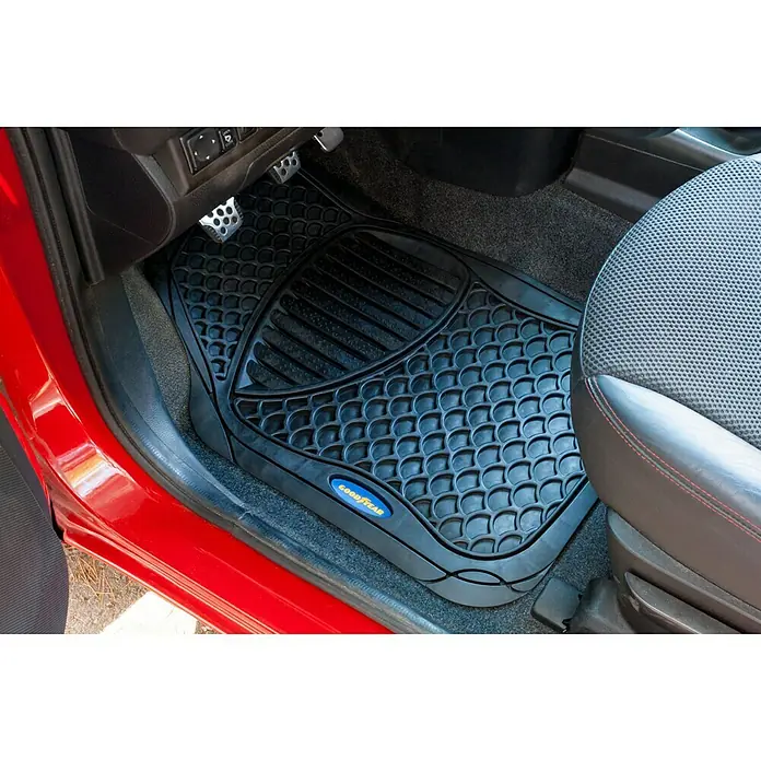 Goodyear Juego de alfombrillas para coche - 4 pzs., Negro - Alfombrilla negra de goma Goodyear con diseño de panal y ranuras antideslizantes en la parte delantera de un coche rojo.