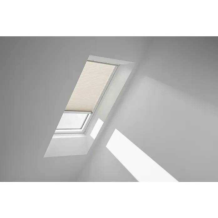 Velux Dachfensterplissee FML UK04 1259KWL - Farbe: Hellbeige - 1259KWL, Farbe Schiene: Weiß, Elektrisch - Ein Dachfenster mit einem beigen Plissee-Rollo, das teilweise geschlossen ist, lässt Licht in den Raum.