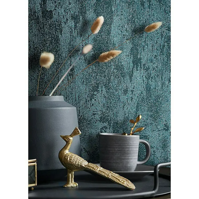 Glööckler Pompöös Provence Vliestapete - Grün/Blau, Metalloptik, 10,05 x 0,53 m - Nahaufnahme von Dekorationsartikeln auf einem Tisch, darunter eine goldene Pfauenfigur, eine graue Tasse und eine Vase mit Pflanzen.