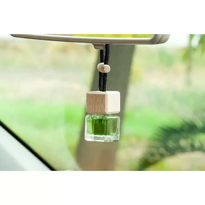 Ambientador de coche para colgar - Manzana, 8 sem. - Ambientador de coche con tapa cuadrada de madera y botella de cristal con líquido verde, colgando del espejo retrovisor.