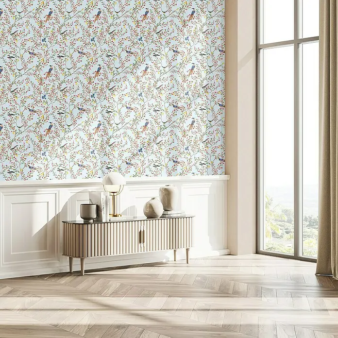 Glööckler Pompöös Provence Vliestapete - Blau/Grün/Rot, Floral, 10,05 x 0,53 m - Ein stilvolles Sideboard mit geriffelten Türen und dekorativen Elementen, das in einem hellen Raum mit Vogelmotivtapete steht.