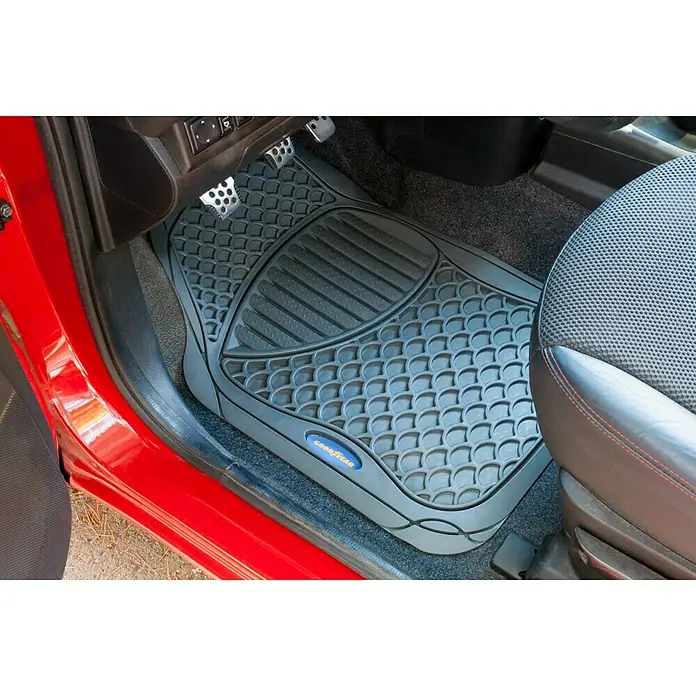 Goodyear Juego de alfombrillas para coche - 4 pzs., Gris - Una alfombrilla gris Goodyear dentro de un coche rojo, diseñada con un patrón de panal y ranuras para atrapar la suciedad.