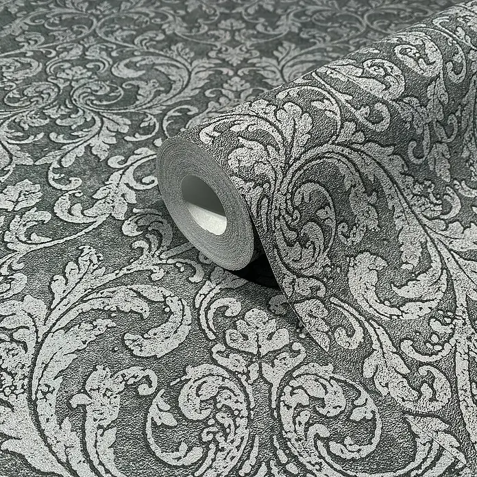 Glööckler Pompöös Provence Vliestapete - Anthrazit/Schwarz, Ornament, 10,05 x 0,53 m - Nahaufnahme einer Rolle grauer Tapete mit einem eleganten, silbernen Damastmuster. Die Tapete ist aufgerollt und zeigt das detaillierte Design.