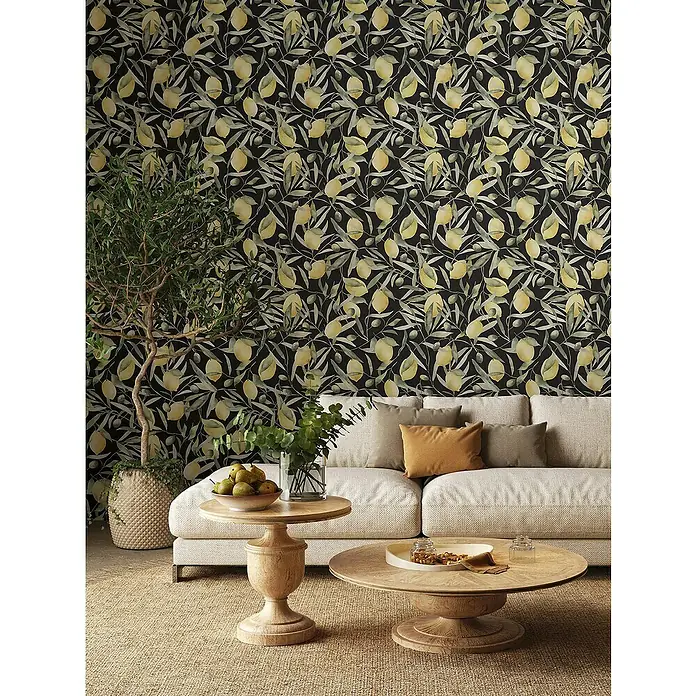 Glööckler Pompöös Provence Vliestapete Zitronen - Schwarz/Grün/Gelb, Floral, 10,05 x 0,53 m - Wohnzimmer mit beigem Sofa, Couchtischen aus Holz und einer Wand mit Zitronenmuster.