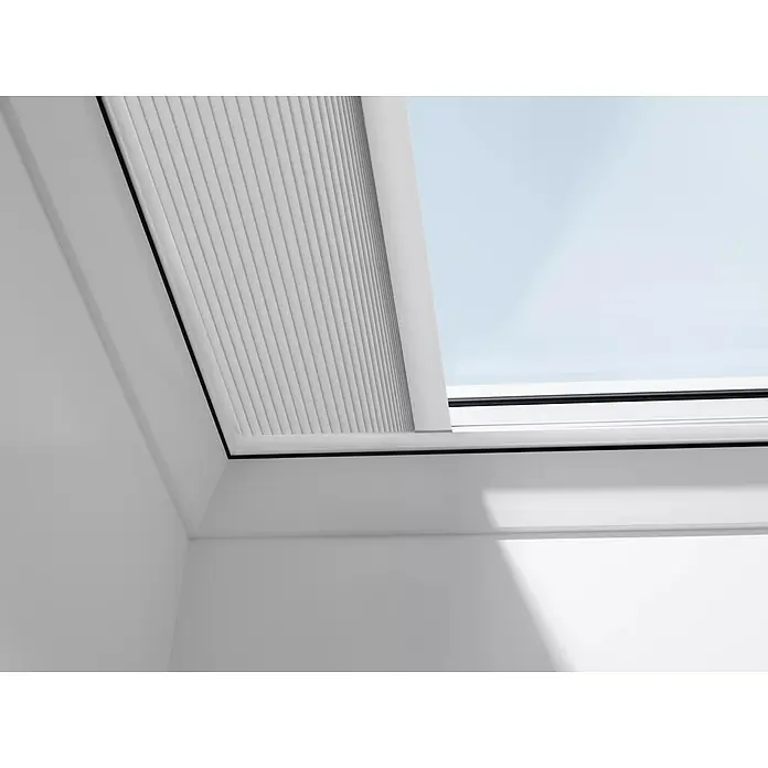 Velux Dachfensterplissee FSK 090090 1045KWL - Farbe: Weiß - 1045KWL, Farbe Schiene: Weiß, Solarbetrieben - Nahaufnahme eines Dachfensters mit einem teilweise heruntergelassenen, weißen Plissee-Rollo, das für sanftes Licht und Privatsphäre sorgt.