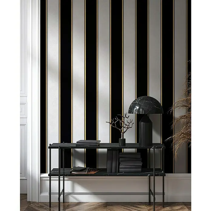 Glööckler Pompöös Provence Vliestapete - Grau/Schwarz, Streifen, 10,05 x 0,53 m - Elegante Konsole mit schwarzer Marmorplatte und passender Lampe, die vor einer stilvollen, gestreiften Tapete platziert ist.