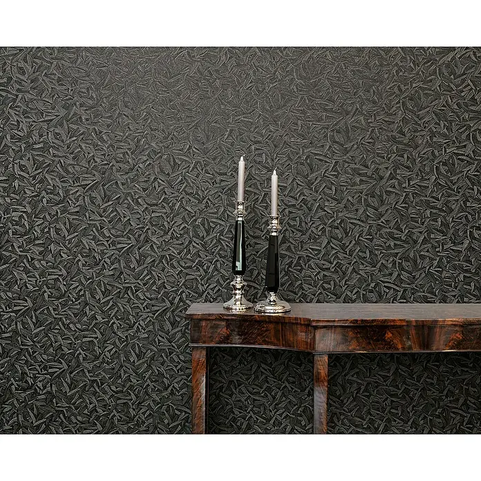 Glööckler Pompöös Provence Vliestapete Basic - Schwarz, Floral, 10,05 x 0,7 m - Zwei kunstvolle Kerzenständer aus Silber und Schwarz stehen auf einer glänzenden Holzkonsole vor einer grauen, gemusterten Wand.