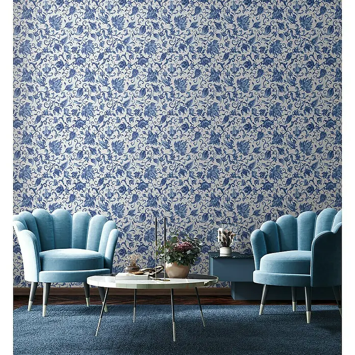 Glööckler Pompöös Provence Vliestapete - Grau/Blau, Floral, 10,05 x 0,53 m - Blaues Wohnzimmer mit zwei Sesseln, einem Tisch und einer passenden blauen Tapete mit floralem Muster. Eine stilvolle und gemütliche Einrichtung.