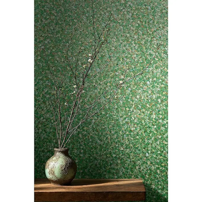 Glööckler Pompöös Provence Vliestapete Basic - Grün, Uni, 10,05 x 0,7 m - Das Bild zeigt eine grüne Keramikvase mit einem Zweig darauf, die auf einem Holztisch vor einer grünen Wand steht.
