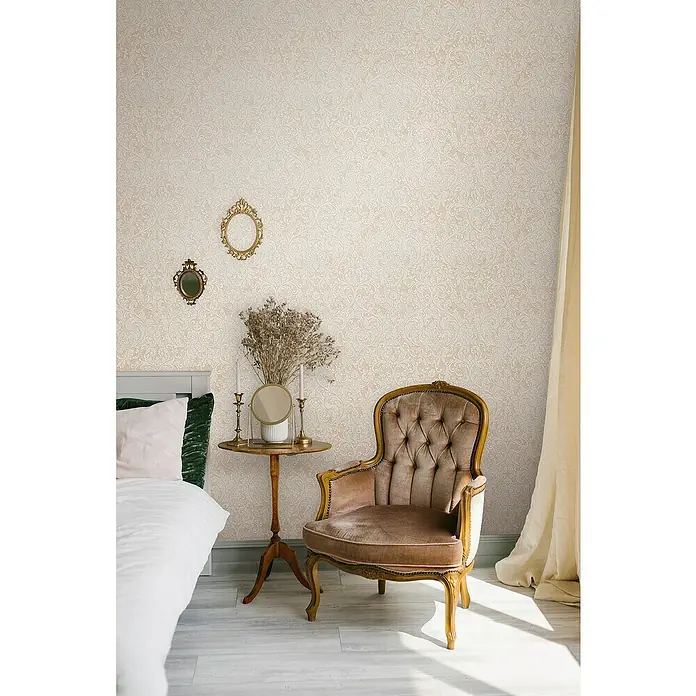 Glööckler Pompöös Provence Vliestapete - Beige/Braun, Ornament, 10,05 x 0,53 m - Elegante Vintage-Zimmergestaltung mit einem prunkvollen Polstersessel als Blickfang, ergänzt durch dekorative Accessoires und eine sanfte Farbpalette.