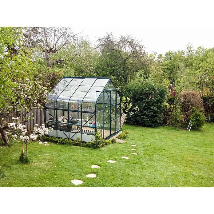 Vitavia Gewächshaus Dione 6700 - Außenmaß inkl. Dachüberstand (B x T): 263,5 x 258 cm, 3 mm, Smaragd - Ein Gewächshaus aus Glas mit Metallrahmen steht im Garten. Der grüne Rasen und die Pflanzen bilden eine idyllische Umgebung.