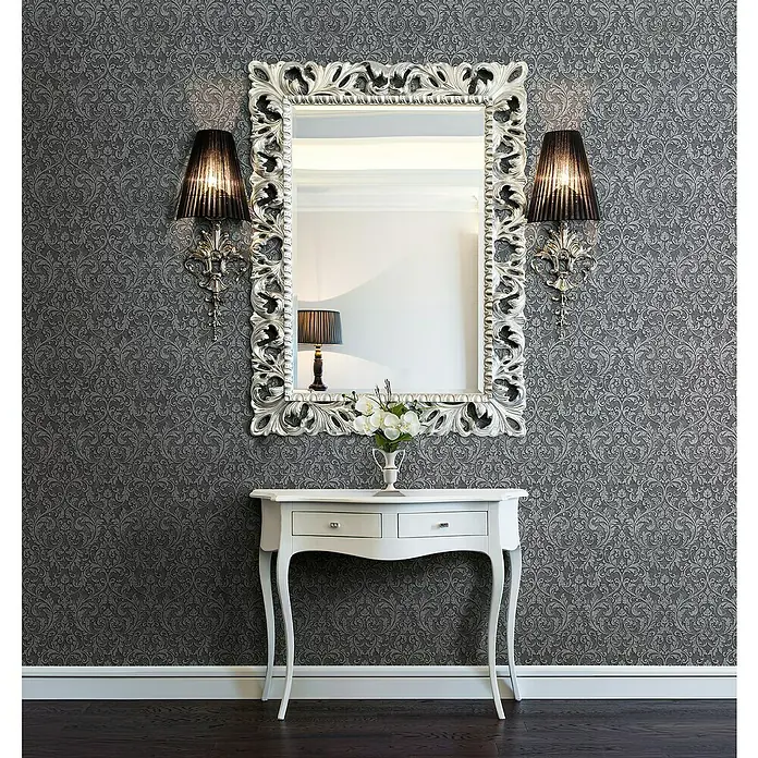 Glööckler Pompöös Provence Vliestapete - Anthrazit/Schwarz, Ornament, 10,05 x 0,53 m - Elegantes Interieur mit einem verzierten Spiegel über einem weißen Konsoltisch, flankiert von Wandleuchten.