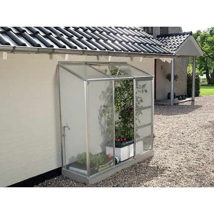 Vitavia Gewächshaus Styx 1300 - Außenmaß inkl. Dachüberstand (B x T): 192,8 x 69 cm, 4 mm, Aluminium - Nahaufnahme eines Gewächshauses mit Pflanzen, das an einer Hauswand steht und eine praktische Gartennutzung ermöglicht.