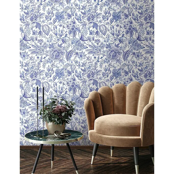 Glööckler Pompöös Provence Vliestapete - Weiß/Blau, Floral, 10,05 x 0,53 m - Beiger Sessel mit dekorativem Beistelltisch vor einer blauen Blumentapete. Elegantes Möbelstück für ein stilvolles Interieur.