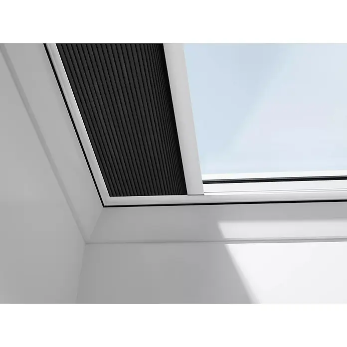 Velux Dachfensterplissee FSK 060060 1047KWL - Farbe: Graphit - 1047KWL, Farbe Schiene: Weiß, Solarbetrieben - Dachfenster mit Verdunkelungsrollo, teilweise geöffnet. Das Rollo ist schwarz und hat eine feine, plissierte Struktur für optimale Lichtkontrolle.