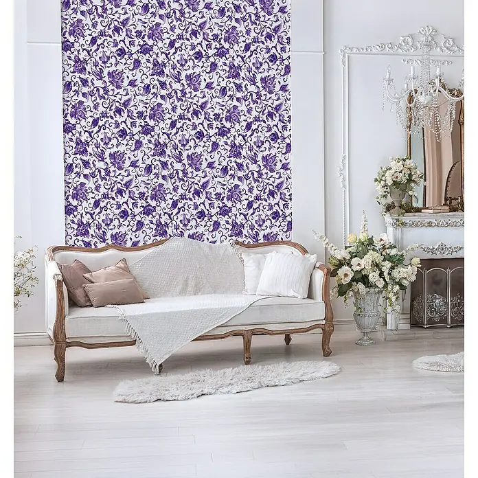Glööckler Pompöös Provence Vliestapete - Grau/Lila, Floral, 10,05 x 0,53 m - Einladender Raum mit einem eleganten Sofa, floraler Tapete und einem Kamin, der eine Atmosphäre von Komfort und Stil vermittelt.