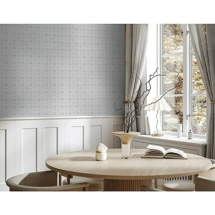 Glööckler Pompöös Provence Vliestapete - Grau, Grafisch, 10,05 x 0,53 m - Elegantes Esszimmer mit rundem Holztisch und Stühlen, dekoriert mit Vase und Buch. Die Tapete im Hintergrund verleiht dem Raum eine stilvolle Note.