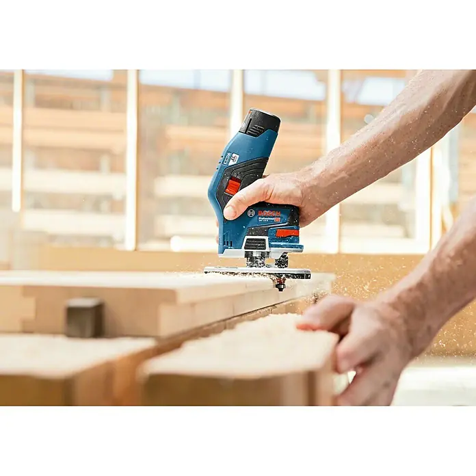 Bosch Professional Akku-Kombifräse GKF 12V-8 L-Boxx - 12 V, Ohne Akku, Leerlaufdrehzahl: 13.000 U/min - Nahaufnahme einer Bosch Professional Akku-Oberfräse beim Bearbeiten von Holz, mit Fokus auf Präzision und Staub.