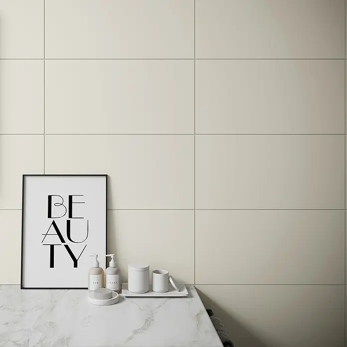 Ambiente by Palazzo Wandfliese Soft Sand - 30 x 60 cm, Creme, Matt - Nahaufnahme von einem Waschbecken mit Kosmetikprodukten, gerahmt von einer "Beauty"-Grafik, vor einem Hintergrund aus cremefarbenen Fliesen.