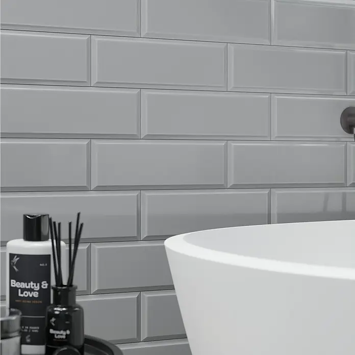 Modern Style Wandfliese Manhattan Biselado Cinze 600 - 9,8 x 29,8 cm, Grau, Glänzend - Nahaufnahme von grauen Metrofliesen mit Badezimmeraccessoires und Badewanne.