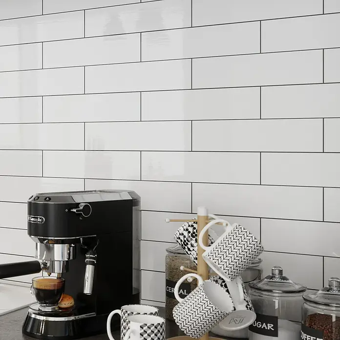 Modern Style Wandfliese Alboran Blanco - 7,5 x 30 cm, Weiß, Glänzend - Küchenszene mit einer DeLonghi Espressomaschine, Kaffeetassen und Vorratsgläsern vor einer Wand mit weißen Metrofliesen.