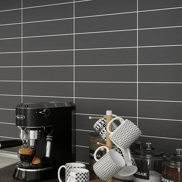 Modern Style Wandfliese Urban Antracita - 7,5 x 30 cm, Anthrazit, Matt - Nahaufnahme einer Espressomaschine mit Tassen, Kaffeebohnen und Zucker vor einer grauen Fliesenwand.
