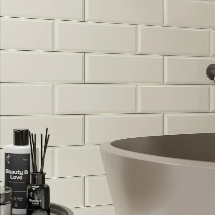Modern Style Wandfliese Metro Biselado Bege 550 - 9,8 x 29,8 cm, Beige, Glänzend - Nahaufnahme der beigen U-Bahnfliesen, die eine stilvolle Badezimmerwand mit Badewanne und Badezusätzen bilden.