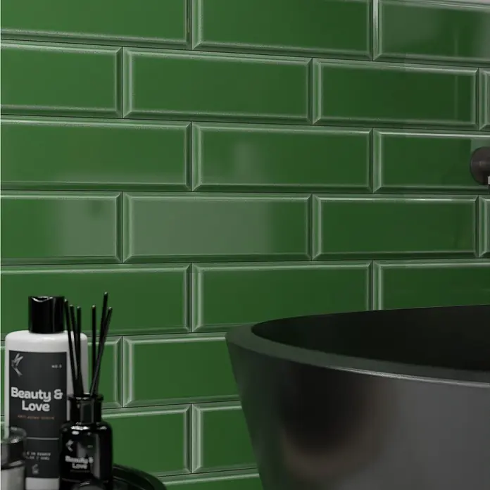 Modern Style Wandfliese Metro Biselado Verde 880 - 9,8 x 29,8 cm, Grün, Glänzend - Nahaufnahme von grünen glänzenden Metrofliesen an einer Wand, mit einem Waschtisch und Pflegeprodukten im Vordergrund.