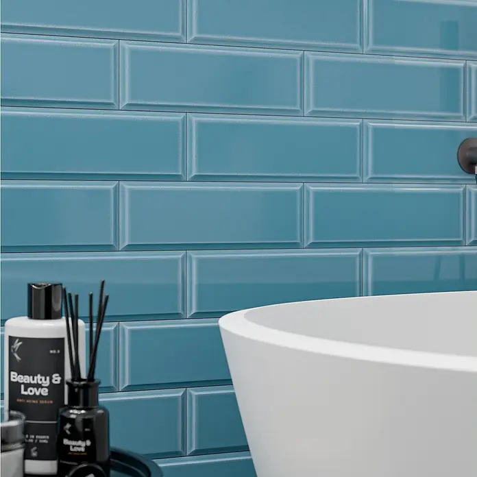 Modern Style Wandfliese Metro Biselado Azul 730 - 9,8 x 29,8 cm, Blau, Glänzend - Detailaufnahme einer Badezimmerwand mit blauen Subway-Fliesen, Badewanne und Pflegeprodukten der Marke "Beauty & Love".