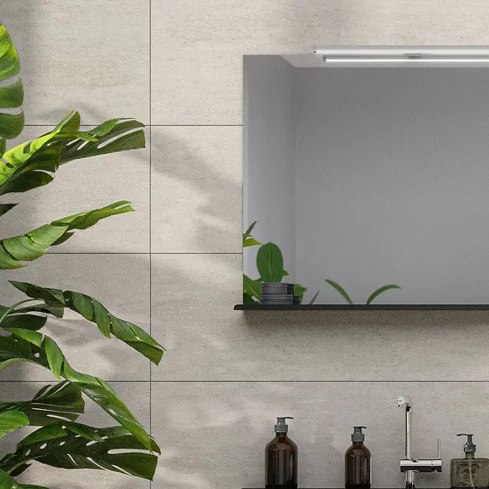 Wandfliese Palmeto Base Gris - 30 x 90 cm, Grau, Matt - Elegantes Badezimmer-Setup mit einem modernen Spiegel, einer stilvollen Ablage und einer Auswahl an Seifenspendern, ergänzt durch eine grüne Pflanze.