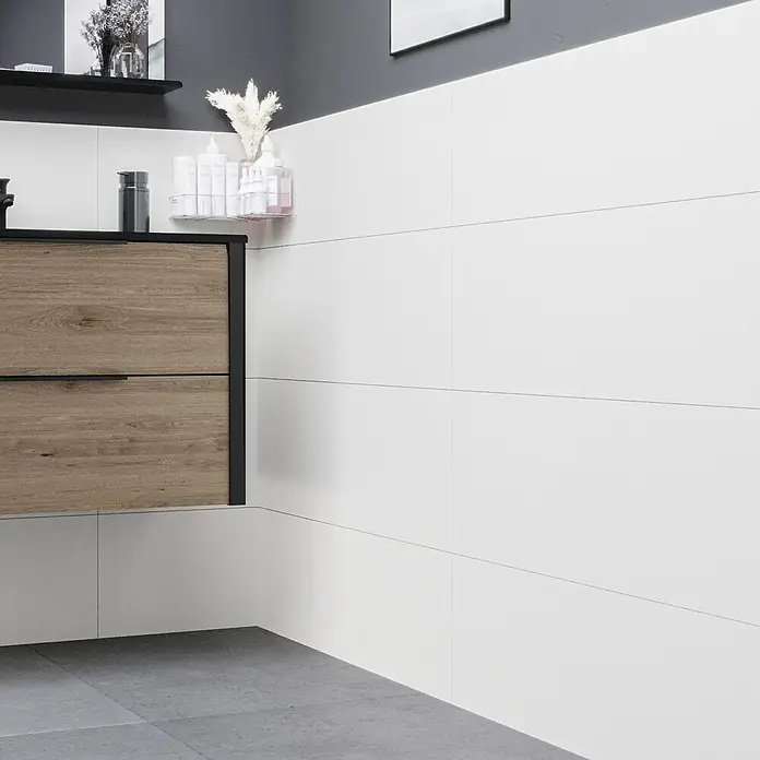 Ambiente by Palazzo Wandfliese Snowwhite - 30 x 90 cm, Weiß, Matt - Ein Badezimmer mit weißen Wandfliesen und einem Holzschrank mit Schubladen. Elegantes Design für moderne Badezimmer.