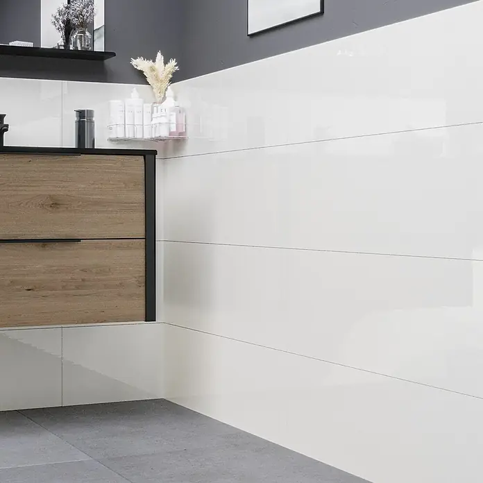 Ambiente by Palazzo Wandfliese Snowwhite - 30 x 90 cm, Weiß, Glänzend - Das Bild zeigt ein Badezimmer mit einer modernen Holzkommode und weißen, glänzenden Wandfliesen, die für ein sauberes und stilvolles Ambiente sorgen.
