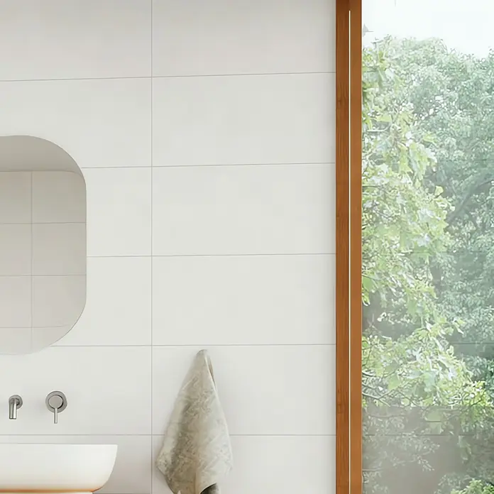 Domicil Wandfliese Living Concrete - 30 x 60 cm, Weiß, Matt - Nahaufnahme eines Badezimmers mit Fliesenwand, Waschbecken und Handtuch, das eine ruhige und elegante Atmosphäre vermittelt.