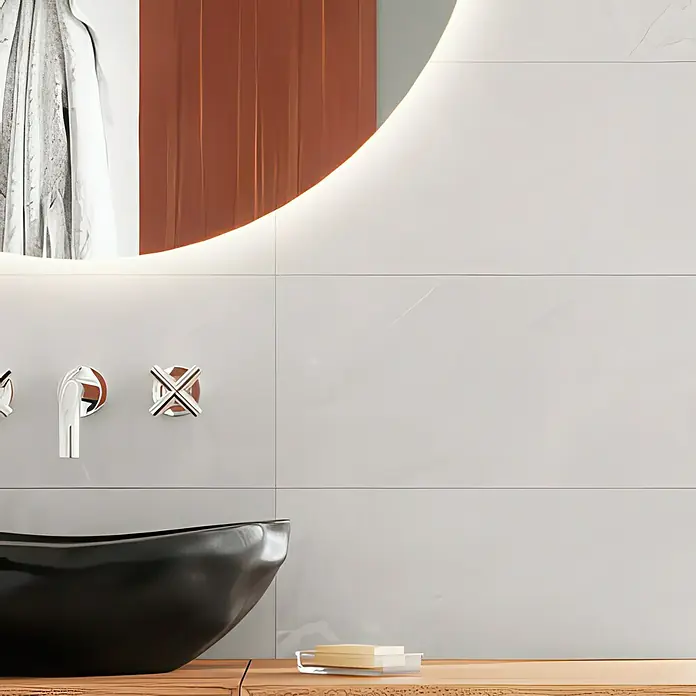 Domicil Wandfliese Stone Art - 30 x 60 cm, Grau, Glänzend - Elegantes Badezimmer-Interieur mit Aufsatzwaschbecken und Armaturen vor einem beleuchteten Spiegel.