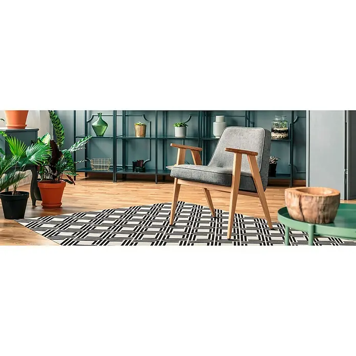 Alfombra de vinilo Living geométrica - Negro, 180 x 120 cm - Acogedor sillón gris con estructura de madera sobre una alfombra geométrica en un elegante salón con plantas y decoración.